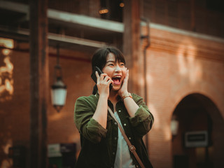 Asian woman using smartphone with happy mood in shopping mall