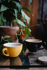 Yellow and black cups with coffee on wooden table