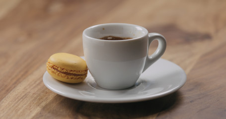 orange macaron on saucer with coffee cup