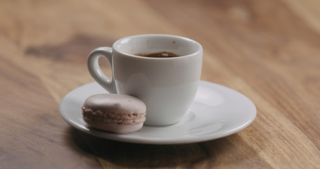 beige macaron on saucer with coffee cup