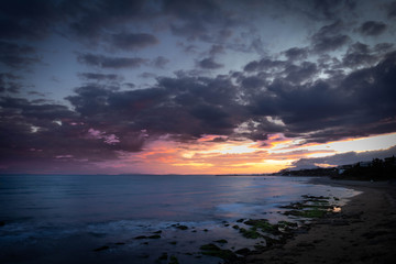 Fototapeta na wymiar Sunset on the edge of the sea. The sky is illuminated with warm colors.