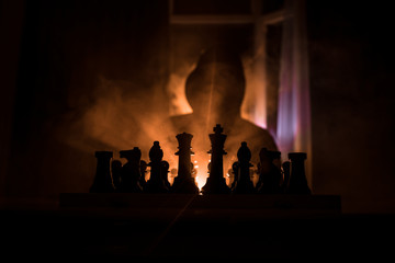 Man playing chess. Scary blurred silhouette of a person at the chessboard with chess figures. Dark toned foggy background.