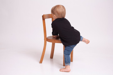 fair-haired boy with a chair in a white studio