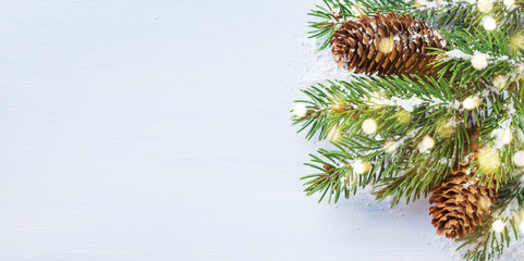 Merry Christmas holiday card or banner with snowy fir branches and conifer cones. Magic bokeh lights.