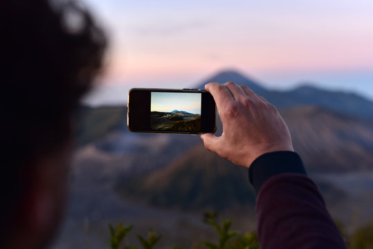 Tourist man taking the photos of Mount Bromo at sunrise, Java Island, Indonesia