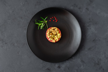 Beef tartare with pickled cucumber and marinated mushrooms on black plate. Dark background.