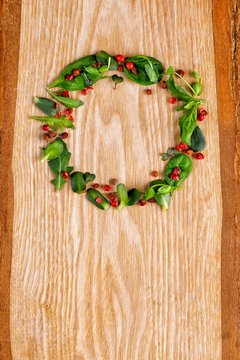 New Year's wreath from microgreen and pepper shinus on a wooden texture.