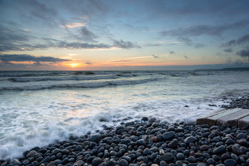 The atlantic waves crash against westward Ho beach in Devon at sunset