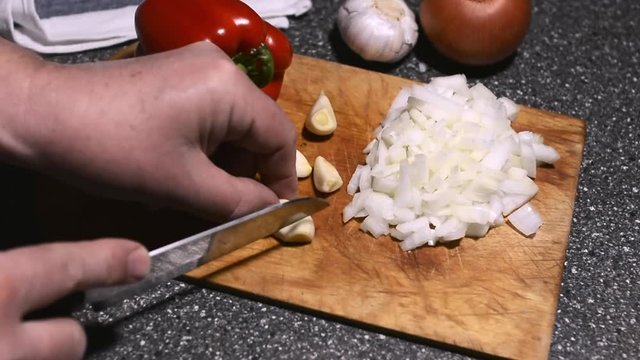 Hand with knife cutting fresh garlic