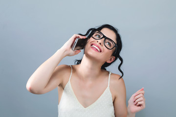 Young woman talking her the cellphone on a gray background