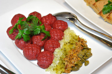 Beef tartare with pickled cucumber, marinated mushrooms and fresh onion on plate.