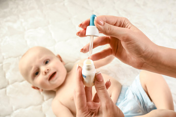 mother holding a baby nasal drops. Baby healthcare concept. naughty baby