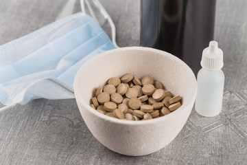 close-up of a tablet with plant extract in a medical ceramic cup on the background of a gauze bandage on a gray background.