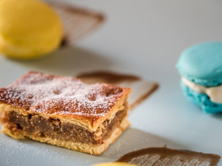 Different macaroons and cake on white plate with chocolate cream. Sweets on white plate with close up view.