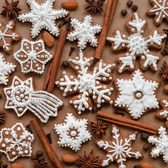 Christmas dekoration with spices and cookies in the shape of snowflakes, cinnamon sticks and star anise on dark brown paper background. Top view.