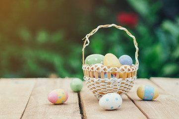 Colorful easter eggs in basket on wooden table win copy space.