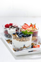 sweet desserts with fresh berries in glasses on white wooden tray, vertical