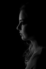 Dark portrait of a beautiful young woman in black and white.