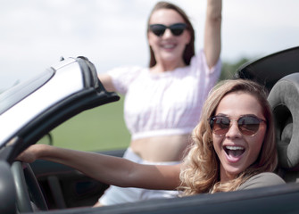 close up.two girlfriends traveling in a convertible car