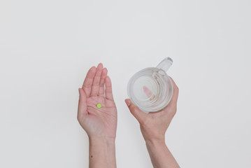 Woman holding pill and glass of water in hands taking emergency medicine, supplements or antibiotic...