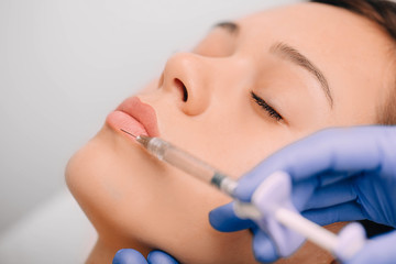woman having lip injections, a prick of a syringe for the beauty lips. lip augmentation - obrazy, fototapety, plakaty