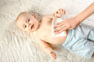 maternal care for babe - wiping the baby skin with wet wipes. funny baby emotions. Baby Care...