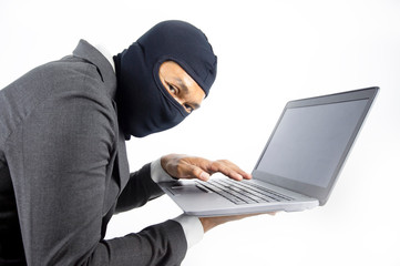 Concentrated trained masked computer hacker at stealing data from computer.