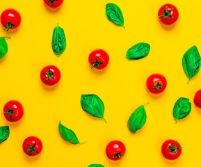 Above view at tomatoes and basil on yellow background