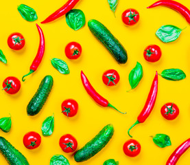 Above view at Chili pepper and tomatoes with cucumbers on yellow background