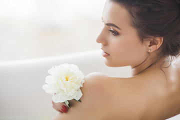 Obraz na płótnie Canvas Young beautiful woman taking bath with milk and flowers