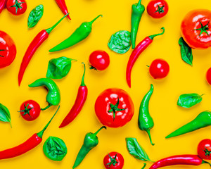 Above view at Chili pepper and tomatoes with basil on yellow background