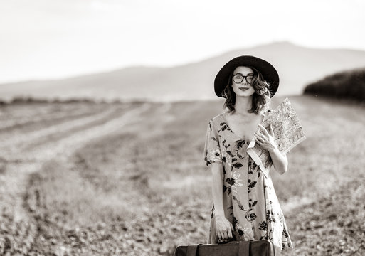 Portrait of young woman in dress with map and suitcase at autumn countryside. Image in black and white color style