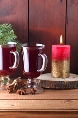 Mulled wine and burning candle on wooden boards. Christmas mulled wine, cinnamon sticks, anise and honey. Alcoholic drink of wine, fruit and honey. Festive drink and Christmas tree branches