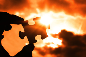puzzle in the hand of a man on the background of the evening sky. missing detail, business vision. thinking.