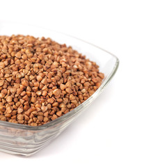 Roasted buckwheat grains in glass bowl isolated on white background