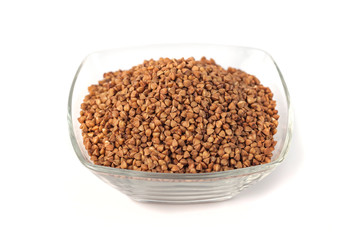 Roasted buckwheat grains in glass bowl isolated on white background