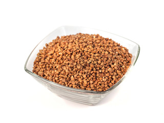 Roasted buckwheat grains in glass bowl isolated on white background