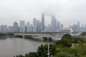 Fototapeta premium Modern city with skyscrapers. City buildings, a bridge across the river, driving cars on the bridge. High towers of a business center. Modern architecture of buildings.