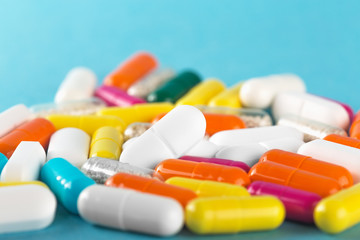 Assorted medical pills and capsules on blue background .