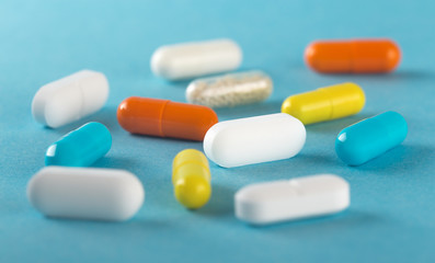 Assorted medical pills and capsules on blue background .