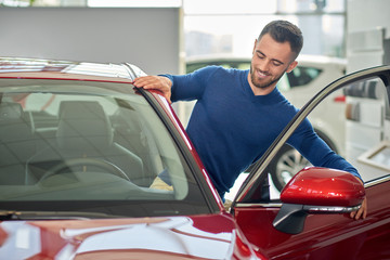 Brunette client with beard testing red car before buying.