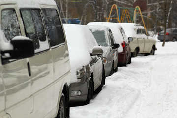 Row of parked cars in line covered with thick layer of snow
