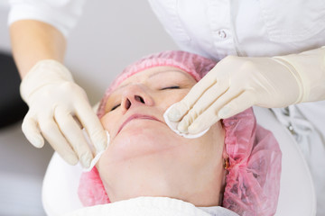 Obraz premium Cosmetologist making injection in face of senior woman. Skin aging, rejuvenation, face lifting procedures. Aged woman gets beauty facial injections in cosmetology clinic.