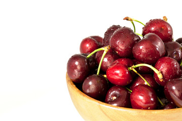 Ripe sweet cherry in wooden bowl isolated on white background closeup.