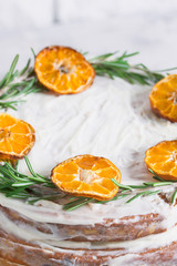 Cake on glass stand decorated with rosemary dried mandarin slices