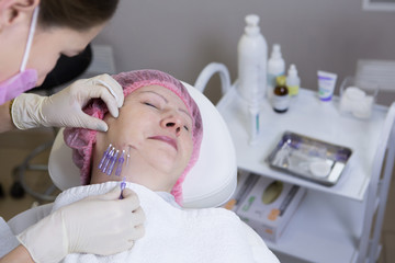 Obraz premium Cosmetologist making injection in face of senior woman. Skin aging, rejuvenation, face lifting procedures. Aged woman gets beauty facial injections in cosmetology clinic.