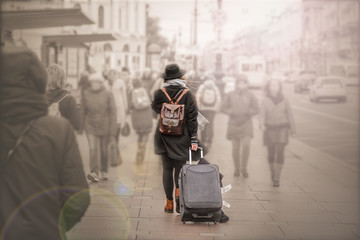 the concept of loneliness among people.a girl in a coat, a hat with a suitcase goes on a journey...