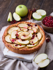 Homemade apple pie and ingredients on wooden background.