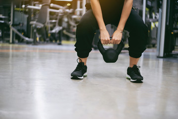 Woman having functional fitness training with kettlebell in sport gym weight lifting and legs squat healthy lifestyle bodybuilding.