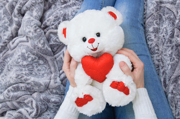Girl in a white sweater holding a teddy bear. View from above.